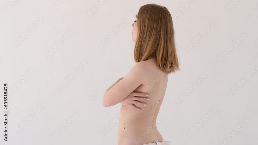 Young woman with bare shoulders and natural facial makeup covers chest with hands looking at camera. Girl with clean fresh skin, skincare cosmetics after effect, white background