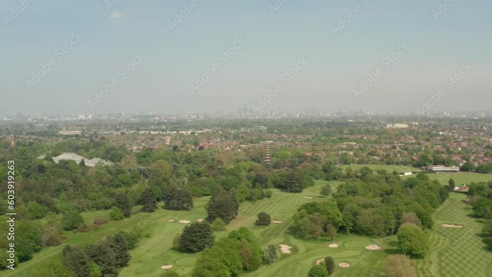 Dolly back aerial shot over large green golf course with London skyline in the background Dolly back aerial shot over large green golf course with London skyline in the background