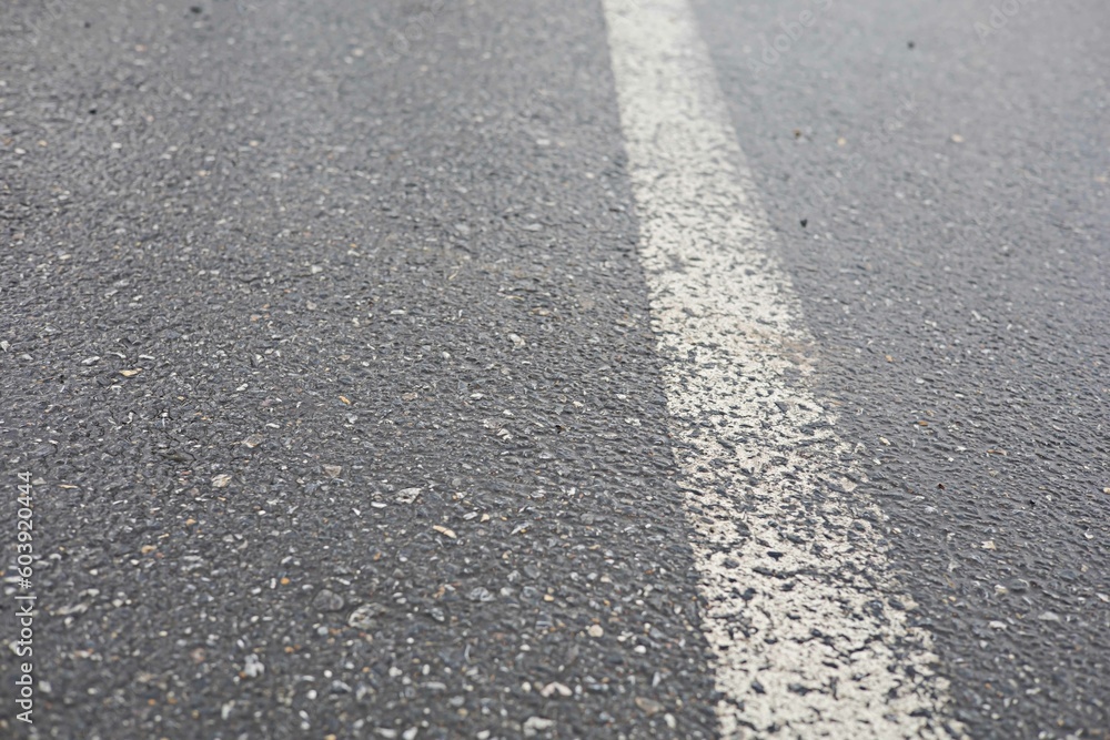 The asphalt road has white traffic lines while the road is wet. The asphalt road has white traffic lines while the road is wet.