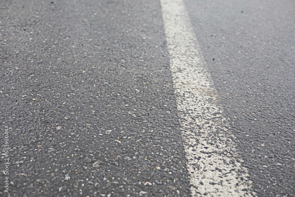 The asphalt road has white traffic lines while the road is wet.