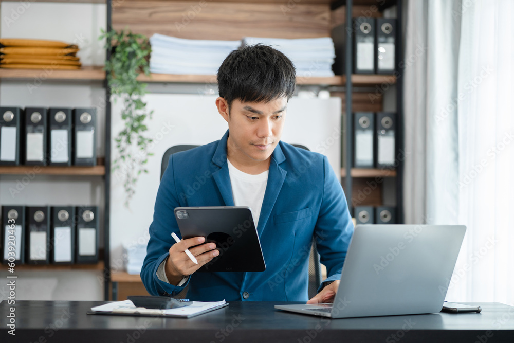 Businessman working at home with tablet and laptop computer and papers on desk. Businessman working at home with tablet and laptop computer and papers on desk.