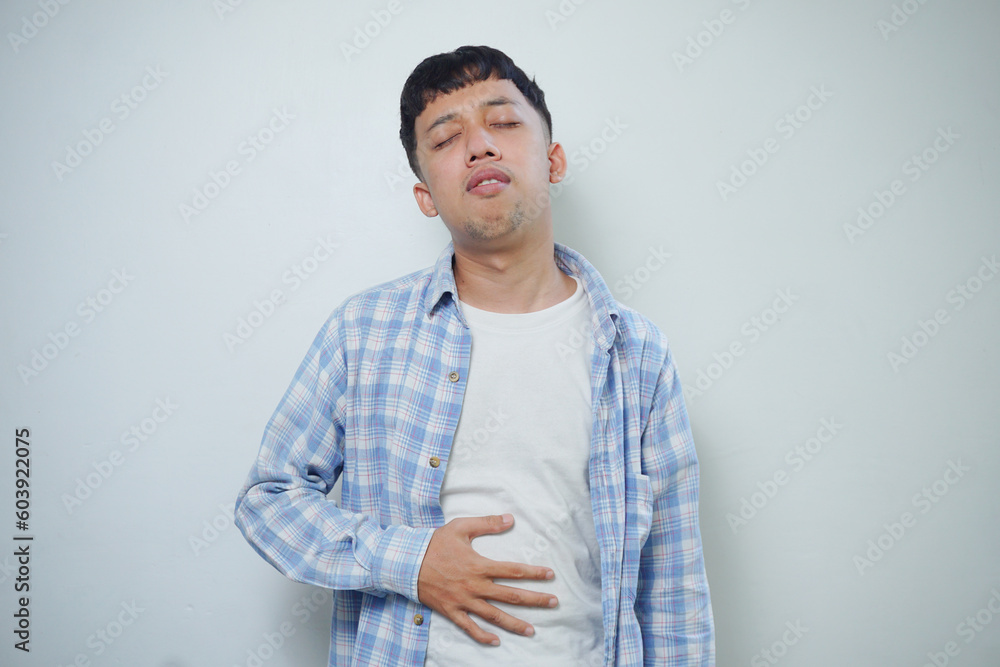 Worried facial expression of Asian man who got problem with stomach isolated on white background Worried facial expression of Asian man who got problem with stomach isolated on white background