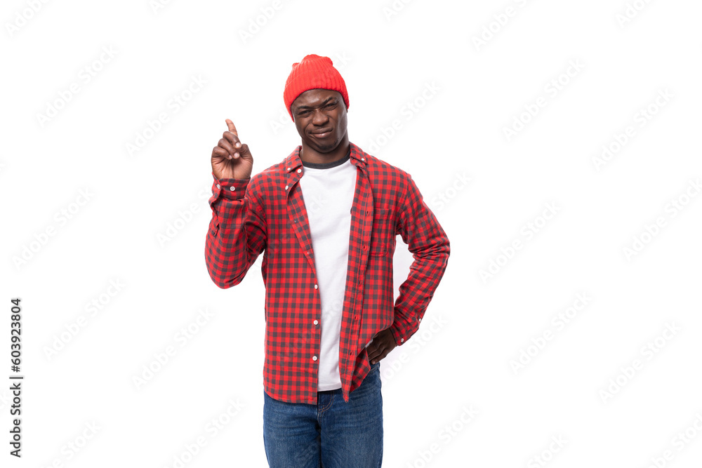 confident young ethnic african guy in red plaid shirt and jeans gesturing over isolated white background