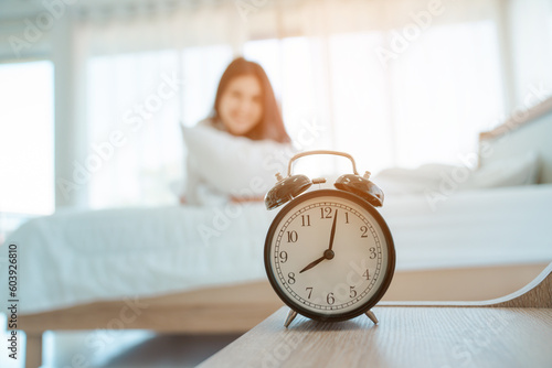 Young woman at home in morning, focus on alarm clock, alarm clock wake up woman in the room