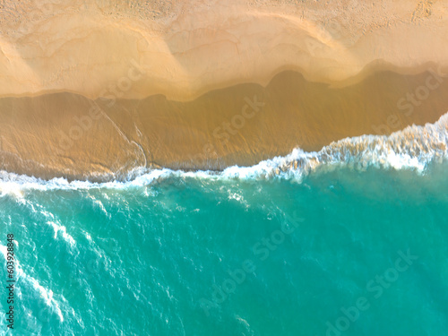 Ocean waves on the beach as a background. Beautiful natural summer vacation holidays background. Aerial top down view of beach and sea with blue water waves 