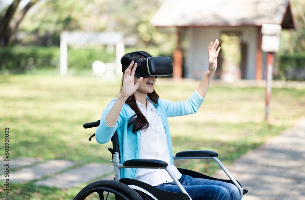 Young asian woman in wheelchair wearing virtual reality touching air during the VR experience. Young asian woman in wheelchair wearing virtual reality touching air during the VR experience.