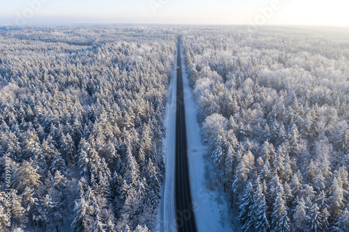 Beautiful winter drone aerial landscape photo - snowy frozen trees and straight road on sunset time, Poland, Suwalszczyzna