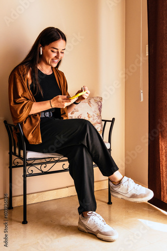 A stylish young woman teleworking with wireless headphones and phone