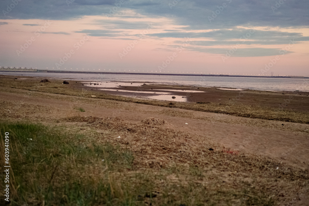 sunset over the sea. Beautiful cloudy evening sky. Dam bridge in the distance