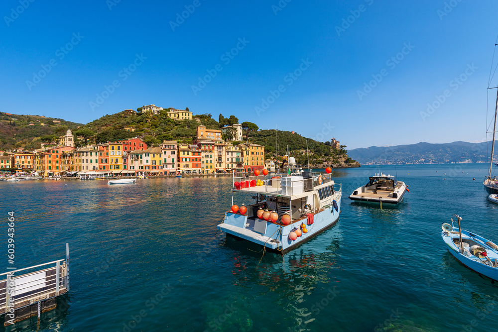 Fishing Boats and Motorboats moored in the famous port of Portofino, luxury Tourist resort in Genoa Province, Liguria, Italy, Europe. Colorful houses, Mediterranean sea (Ligurian sea).