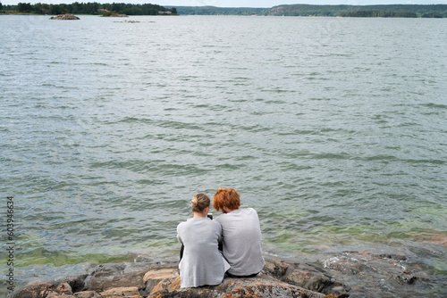 Couple sitting on rocks by sea photo