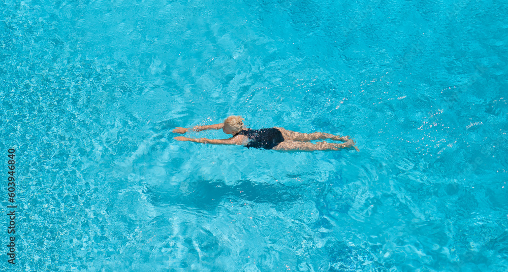 View from the height of the flight of a bird, a woman in a swimsuit swims in a blue pool, rests and relaxes