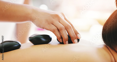 Woman, hands and rock massage at spa in relax for zen, physical therapy or treatment at resort. Hand of masseuse and female person with hot stone back for muscle relief, peace or wellness at a salon