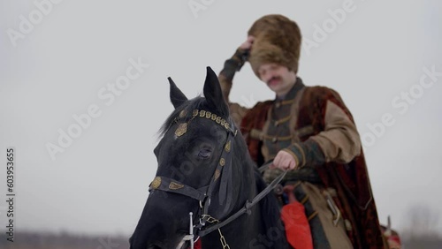 portrait of charismatic man on horse in winter, historical reconstruction of ancient Ruthenia photo