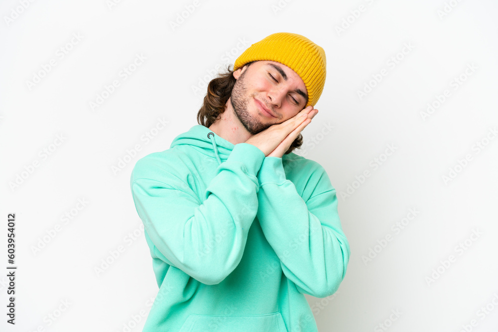 Young handsome man isolated on white chroma background making sleep gesture in dorable expression