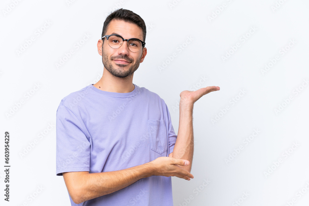 Young caucasian man isolated on white background extending hands to the side for inviting to come Young caucasian man isolated on white background extending hands to the side for inviting to come