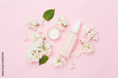 Composition with cosmetic bottles and flowers on color background, top view