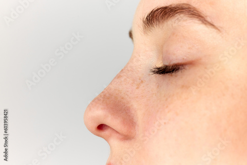 Young woman, girl demonstrating nose after, before surgery over white studio background. Side view. Rhinoplasty photo