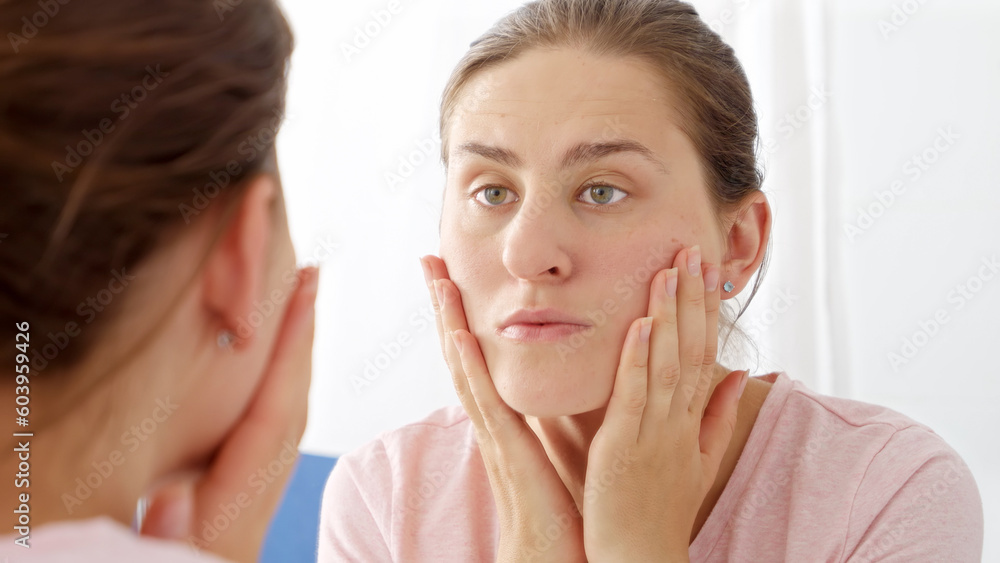 Closeup portrait of beautiful young woman checking for new wrinkles and pimples on her face skin. Concept of female aging, skin issues, facial treatment and care. Closeup portrait of beautiful young woman checking for new wrinkles and pimples on her face skin. Concept of female aging, skin issues, facial treatment and care.