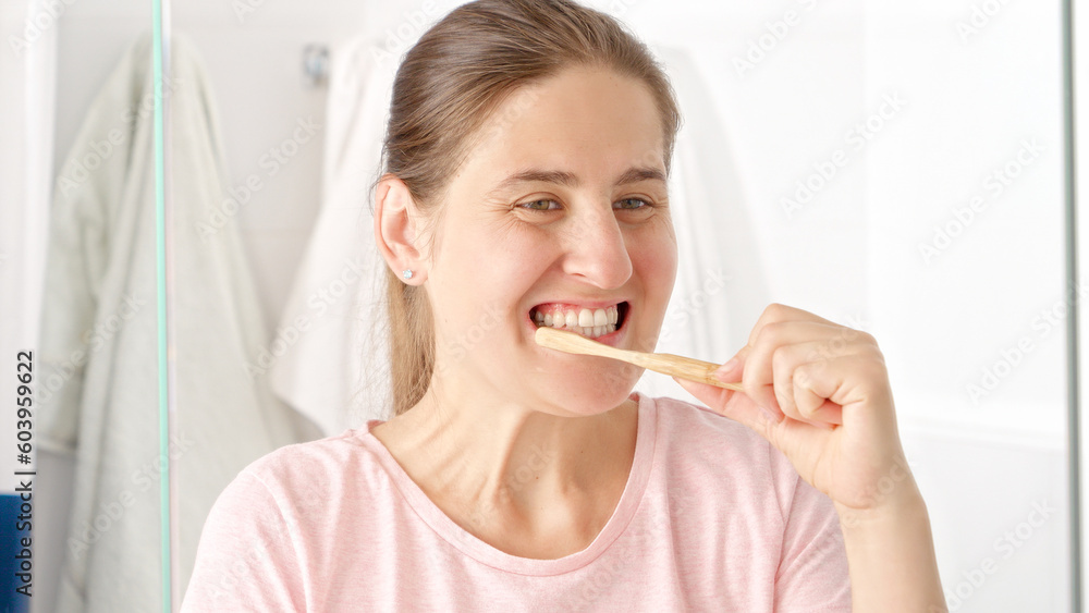 Beautiful young woman brushing her teeth at the mirror in bathroom. Concept of teeth health, self checking mouth and oral hygiene. Beautiful young woman brushing her teeth at the mirror in bathroom. Concept of teeth health, self checking mouth and oral hygiene.