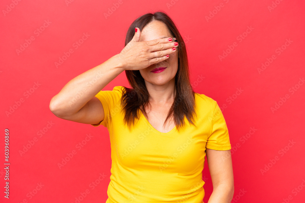 Middle-aged caucasian woman isolated on red background covering eyes by hands. Do not want to see something Middle-aged caucasian woman isolated on red background covering eyes by hands. Do not want to see something