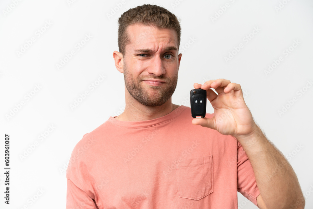 Young caucasian man holding car keys isolated on white background with sad expression Young caucasian man holding car keys isolated on white background with sad expression
