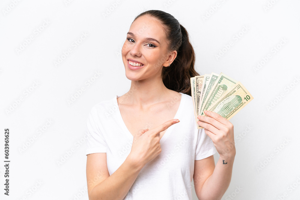 Young caucasian woman taking a lot of money isolated on white background pointing to the side to present a product Young caucasian woman taking a lot of money isolated on white background pointing to the side to present a product