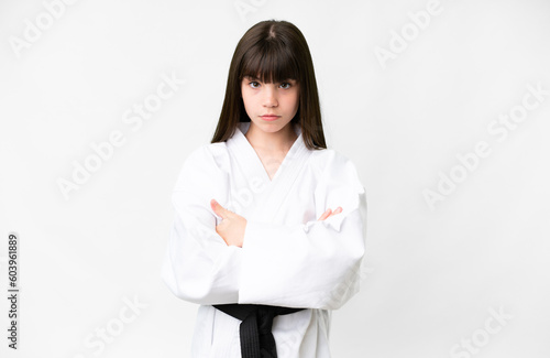 Tablou canvas Little caucasian girl over isolated white background doing karate keeping the ar