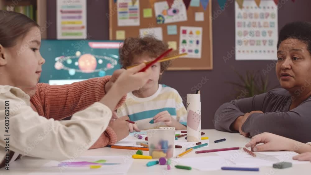 Zoom out of multiethnic group of kids and Black female teacher drawing ...