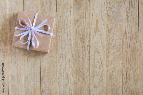 Gift box with bow on wooden background with copy space