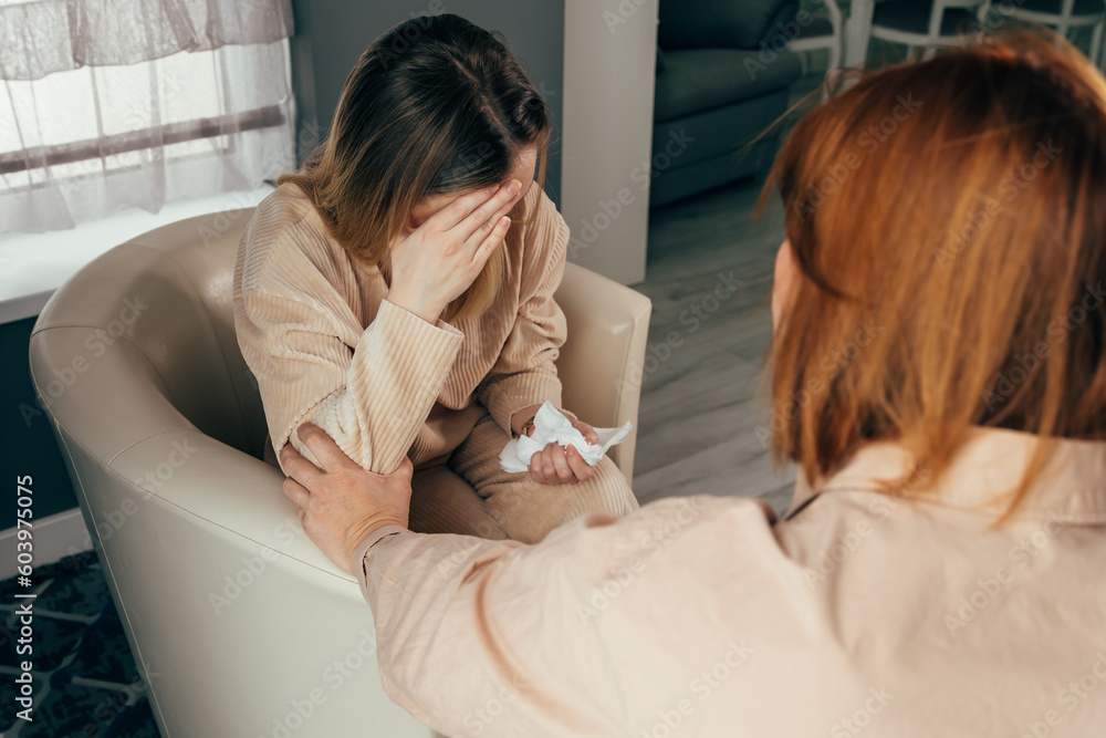 Woman finds solace in the confidence and support of her therapist during a counseling session. The psychologist takes notes to ensure that the therapy remains confidential. Comforting friend.