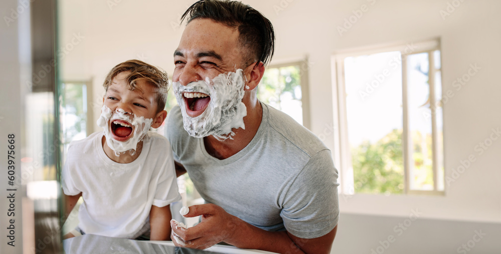 Fun on father's day: Dad and his son have fun shaving together - obrazy, fototapety, plakaty 