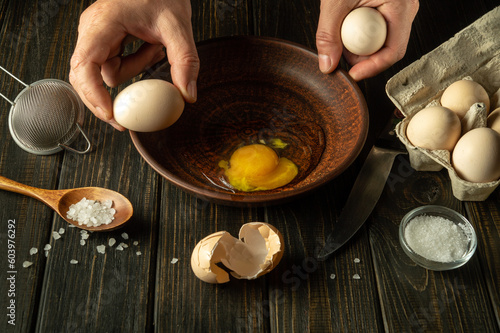 The process of cooking or frying eggs in the kitchen. The cook prepares eggs on the kitchen table for an omelette