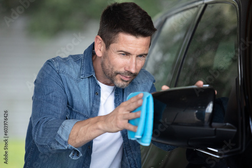 middle age man cleaning his car outdoors