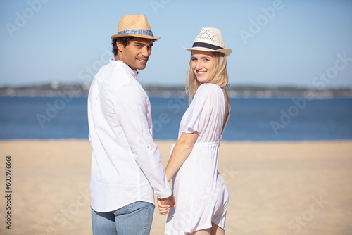 happy young couple holding hands and laughing on the beach