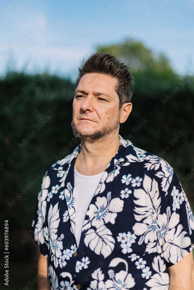 Portrait of a mature man with sideburns dressed in Hawaiian shirt outdoors in a garden. Men's fashion and beauty in travel and vacation. Portrait of a mature man with sideburns dressed in Hawaiian shirt outdoors in a garden. Men's fashion and beauty in travel and vacation.