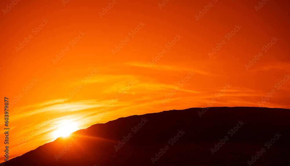 Sky with a Black Mountain Silhouette. Play of Light and Shadow. sun set above horizon line. Sunset above horizon line with sun setting down behind mountains and sun rays. mountains peak. sun beam.