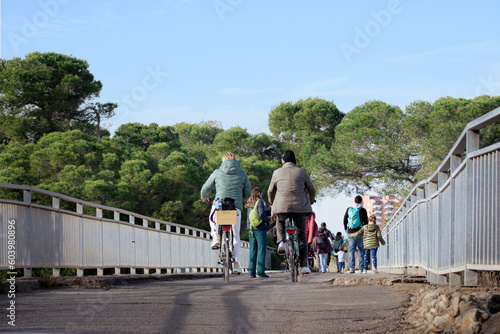 Active group of people outdoors, back wide view. Leisure stroll and walking time and a couple man and woman in bicycle. Activity at nature with casual clothing. Bike ride. El Saler, Valencia Spain
