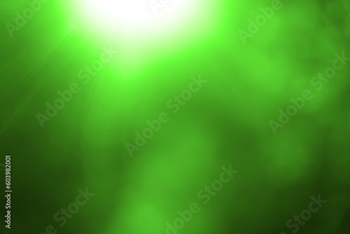 Beautiful colorful sunny summer natural background with bright sunshine. Blurry abstract charming vibrant green bokeh of out of focus shiny leaves in park or forest. summertime, spring season. rays