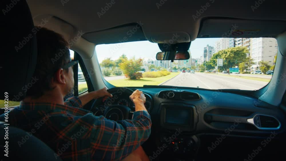 Man drives car in the city. Amateur male driver in casual clothes steers the car in a city and goes fast on the left lane Man drives car in the city. Amateur male driver in casual clothes steers the car in a city and goes fast on the left lane