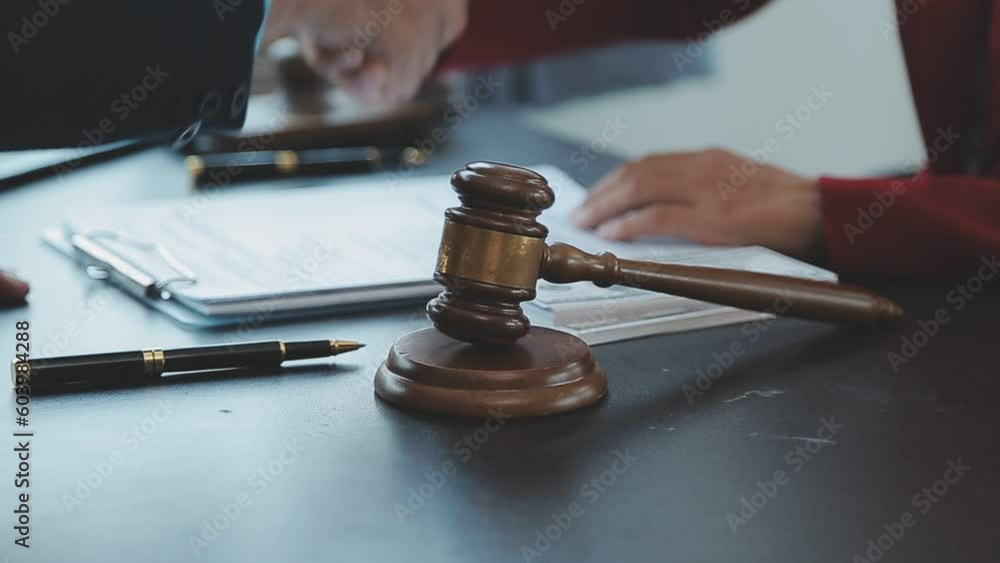 Justice and Law concept. Legal counsel presents to the client a signed contract with gavel and legal law or legal having team meeting at law firm in background Justice and Law concept. Legal counsel presents to the client a signed contract with gavel and legal law or legal having team meeting at law firm in background