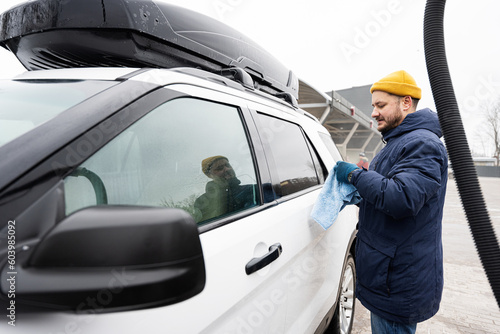 Man wipes american SUV car with a microfiber cloth after washing in cold weather. © AS Photo Family