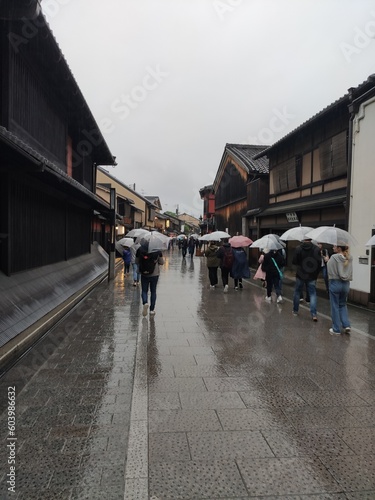 L'insolite et touristique quartier de Gion, avec des petites ruelles à l'asiatique, de l'ancien Japon, sous un temps de pluie, avec ciel nuageux, des gens se promenant avec des parapluies