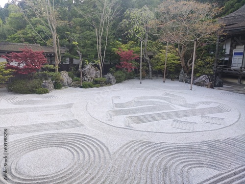 Jardin d'un monastère japonais au mont Koya, avec ruisseau d'eau, sa zone de pierres et de dessins asymétriques, ses arbustes de verdure taillés, prolongeant d'une terrasse bois et coloration