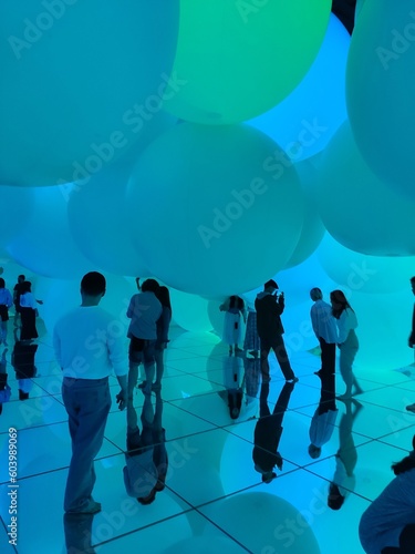Grande salle remplie de grands ballons gonflables, fortement colorés de différentes couleurs, avec des personnages, plongés dans un univers sombre, flou, magique et envoûtant, musée numérique, teamlab photo