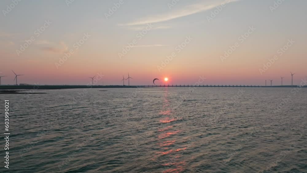 Kitesurfer in front of the Oosterschelde storm surge barrier during sunset, drone shot. Kitesurfer in front of the Oosterschelde storm surge barrier during sunset, drone shot.