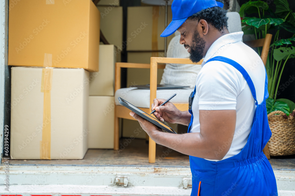 Moving company employee checks boxes in a small truck before sending them to the homeowner. Moving company employee checks boxes in a small truck before sending them to the homeowner.