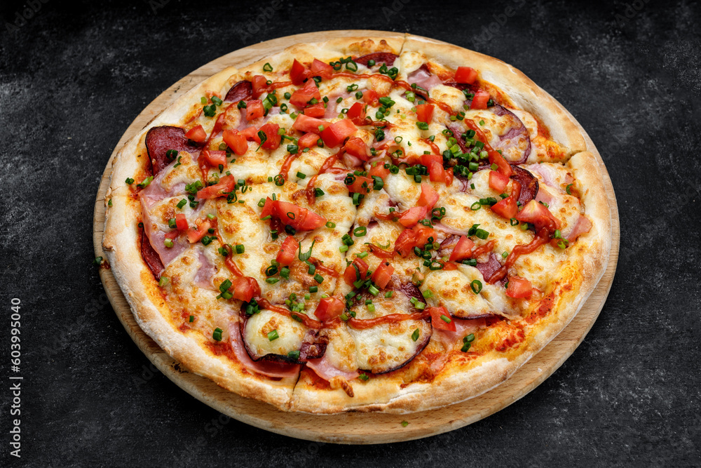 Pizza with cheese, smoked meat, tomatoes, sausage and ketchup, close-up
