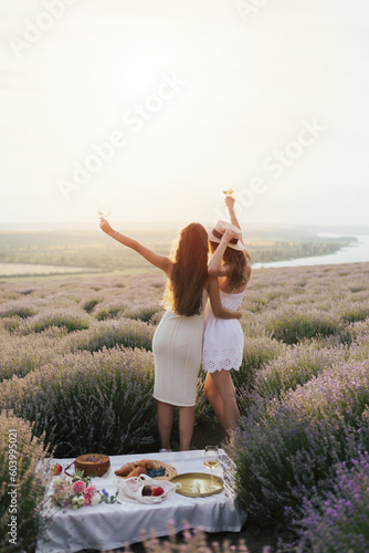 Obraz na płótnie Back view of two female friends walking outdoors at the lavender field. They enjoying fresh air, beautiful nature. w salonie