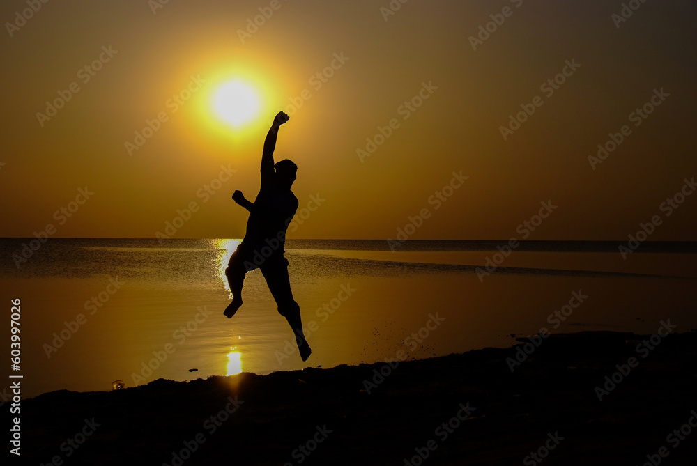 Trying to catch the sun by hand in a silhouette on the beach
